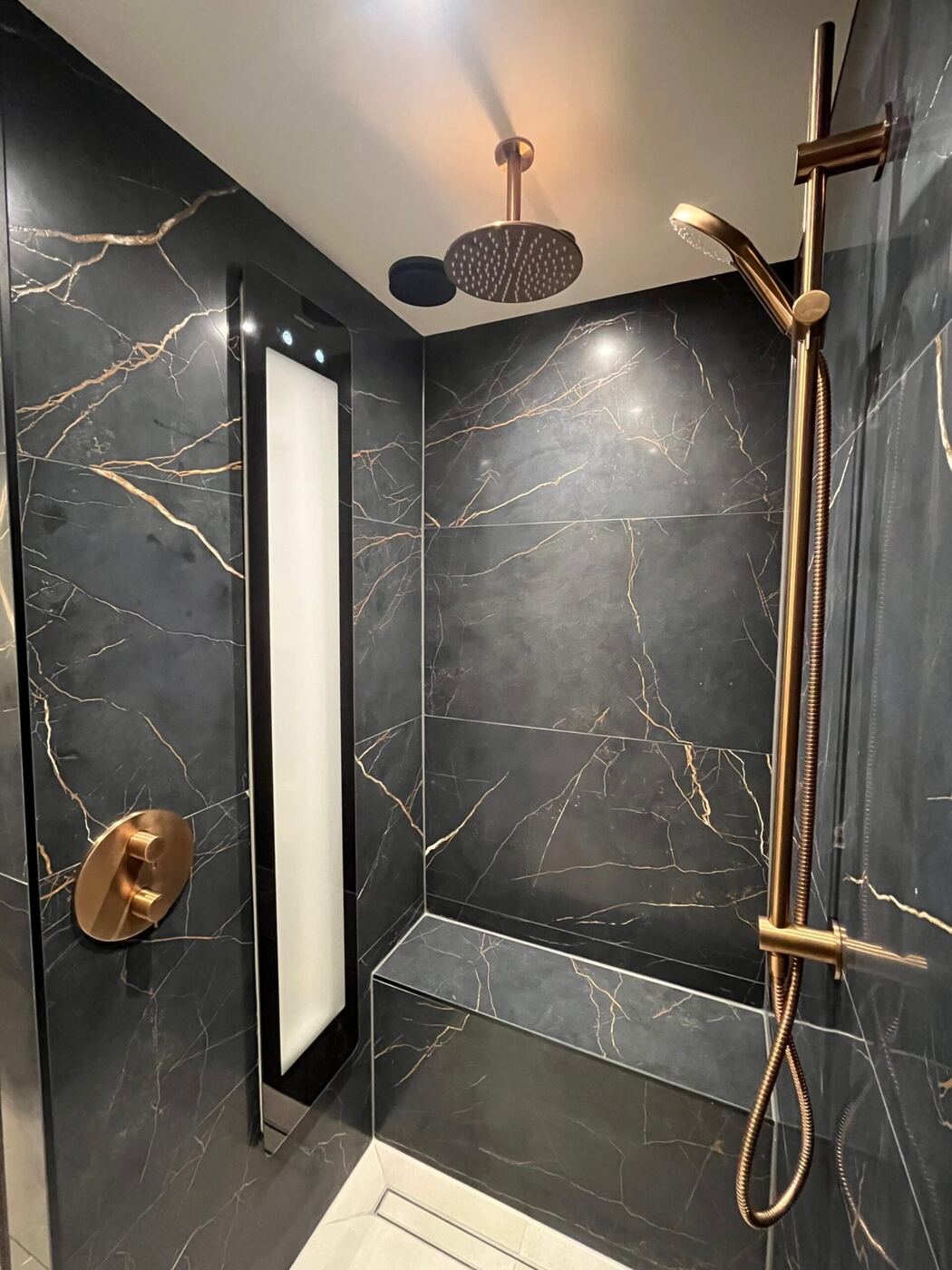 Badkamer met donkere marmerlook tegels en hangtoilet