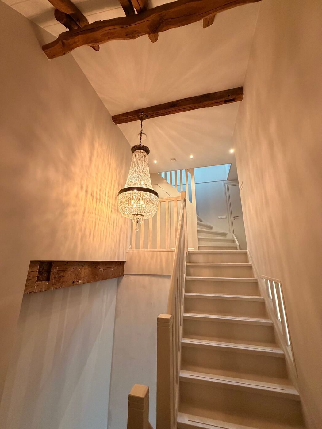 Trappenhuis met houten balken en hanglamp, verlicht